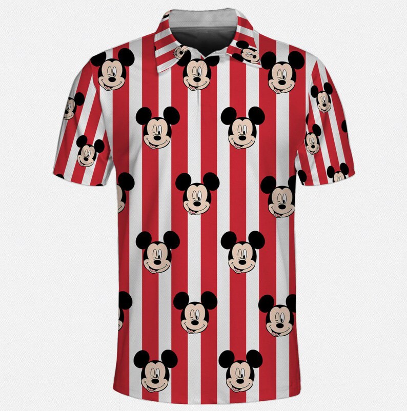 Puede incluir: Un polo de manga corta con un patr&oacute;n repetido de caras de Mickey Mouse sobre un fondo a rayas rojas y blancas. La camisa tiene cuello y cierre de botones. El dise&ntilde;o es una representaci&oacute;n l&uacute;dica y colorida de un personaje de dibujos animados cl&aacute;sico.