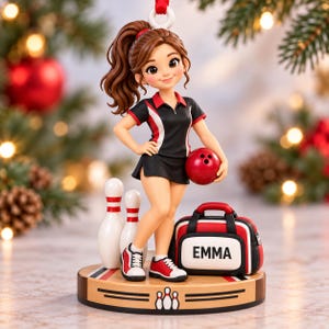 May include: A figurine of a bowling player with brown hair in a ponytail, wearing a black and red shirt and skirt, holding a red bowling ball. Beside the figure are two white bowling pins and a black and red bowling bag labeled EMMA.