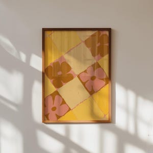 Könnte beinhalten: Ein gerahmter Druck mit einem geometrischen Muster aus rosa und gelben Blumen auf gelbem Hintergrund.