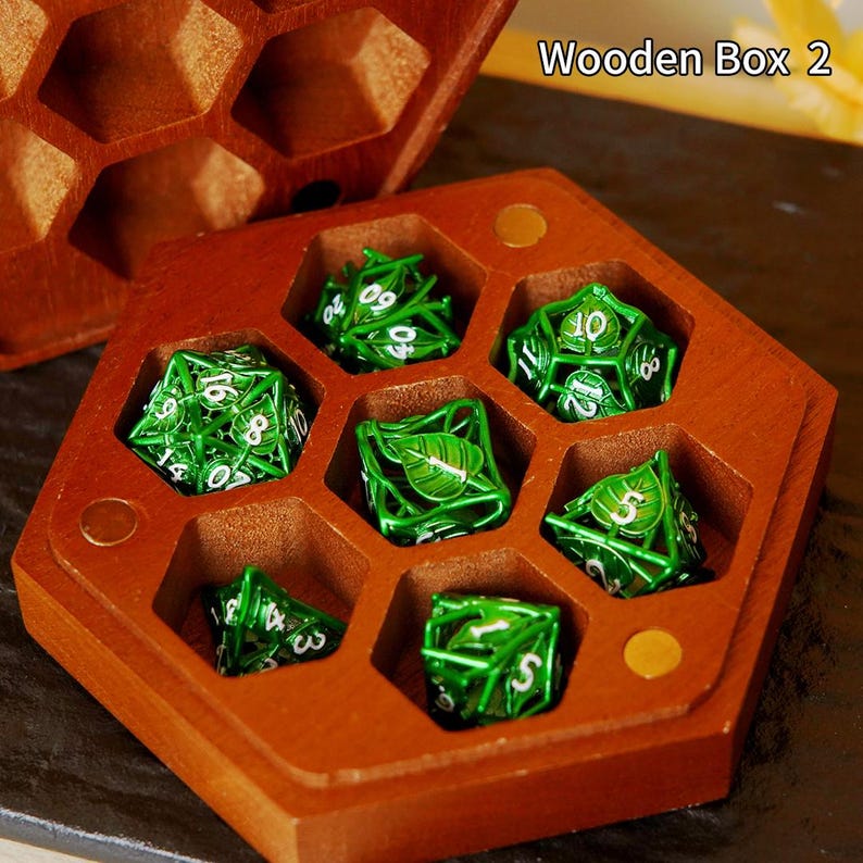 May include: A hexagonal wooden box in reddish-brown, containing seven green dice with white numerals. The dice feature a leaf design. The text "Wooden Box 2" is visible. The box is designed to hold the dice.
