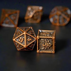 May include: Close-up of several bronze-colored dice, including a D20 die with the number 13 visible. The dice have an aged, metallic appearance with intricate detailing. The dice are likely for tabletop gaming.
