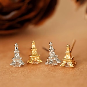 Puede incluir: Tres pares de pendientes con un diseño de Torre Eiffel en miniatura. Los pendientes están disponibles en plata y oro.