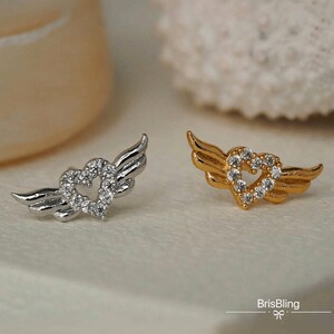 Puede incluir: Dos pares de pendientes con un dise&ntilde;o de coraz&oacute;n y alas. Un par es de plata con cristales transparentes y el otro par es de oro con cristales transparentes.