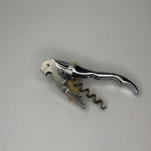 May include: A chrome-plated corkscrew with a lever handle and a worm. The corkscrew is designed to remove corks from wine bottles. The handle is curved for easy gripping. The worm is a spiral shape that screws into the cork.
