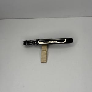 May include: A white ceramic mug with a black handle and the text "But First, Coffee" in a bold, black font. The mug is set against a neutral background, highlighting its simple design.