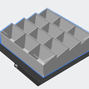 Peut inclure: Unité de stockage grise à plusieurs compartiments, avec un contour bleu, posée sur une base noire. L'unité est divisée en sections rectangulaires, créant un design en escalier. L'image est un rendu 3D.