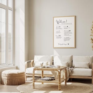 May include: A light-filled living room with a neutral color palette. A framed sign with the word "Welcome" hangs above a cream-colored sofa. A round jute rug, a woven ottoman, and a bamboo coffee table complete the cozy, inviting space.