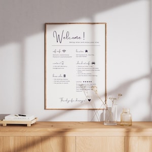 May include: A framed sign with the word "Welcome!" in elegant script, along with information about the property. The sign is on a wooden surface with a small vase and a decorative tray.