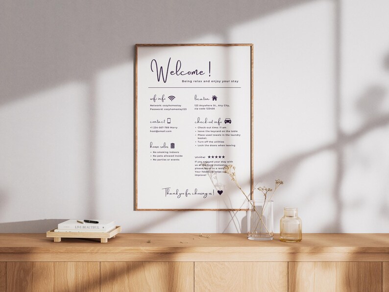 May include: A framed sign with the word "Welcome!" in elegant script, along with information about the property. The sign is on a wooden surface with a small vase and a decorative tray.