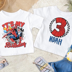 Pu&ograve; includere: Due magliette bianche con grafiche di Spider-Man. Una maglietta dice "IT'S MY Birthday" con un'illustrazione di Spider-Man. L'altra maglietta ha il numero 3 con un design a ragnatela e il nome "NOAH" in blu.