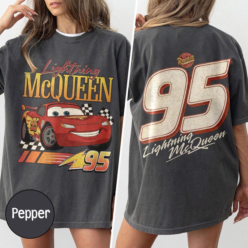 May include: Pepper-colored t-shirt featuring Lightning McQueen from the Cars movie. The front displays the character and text, while the back shows a large "95" and the character's name. The shirt has a vintage, distressed look.