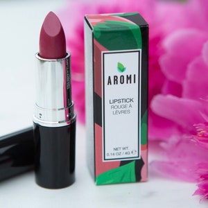 May include: A black and silver lipstick tube with a pink lipstick bullet. The lipstick is in a box with a green and pink design and the text "AROMI LIPSTICK ROUGE A LEVRES NET WT. 0.14 OZ / 4.0 G".