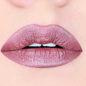 Peut inclure: Gros plan sur les lèvres d'une personne portant un rouge à lèvres rose doré métallique.