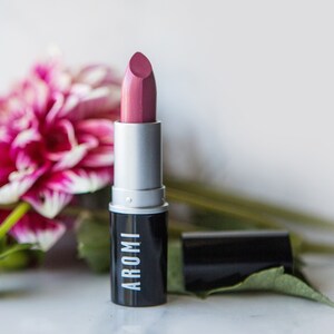 K&ouml;nnte beinhalten: Ein rosa Lippenstift in einem silbernen und schwarzen R&ouml;hrchen. Auf dem R&ouml;hrchen steht in wei&szlig; "AROMI" gedruckt.