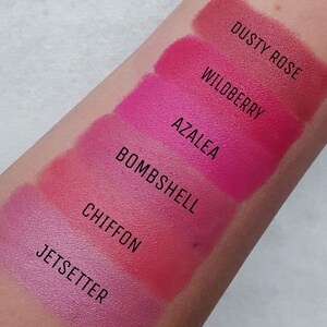 K&ouml;nnte beinhalten: Farbtupfer von sechs verschiedenen Lippenstiftfarben auf dem Arm einer Person. Die Farben sind von hell nach dunkel beschriftet: Jetsetter, Chiffon, Bombshell, Azalea, Wildberry und Dusty Rose.