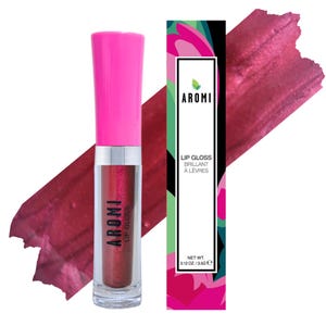 Könnte beinhalten: Eine transparente Lipgloss-Tube mit leuchtend pinkfarbenem Deckel und silbernem Band. Die Tube enthält einen schimmernden, rötlich-braunen Glanz. Das Produkt ist mit "AROMI LIP GLOSS" beschriftet. Ein passender Farbton und eine Produktbox sind ebenfalls sichtbar.