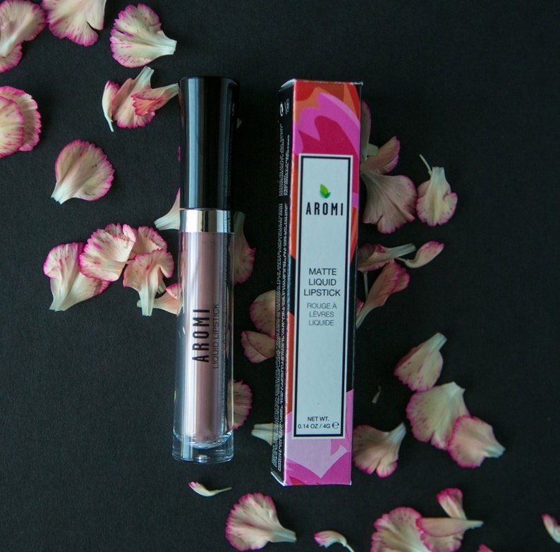 May include: Aromi Matte Liquid Lipstick in a mauve shade with a black and silver tube. The packaging features a pink and green floral design with the brand name "Aromi" and the product name "Matte Liquid Lipstick".