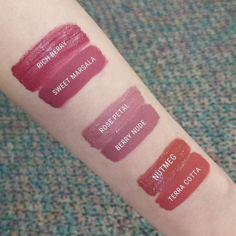 May include: Swatch of five different shades of lipstick on a person's arm. The shades are labeled "Rich Berry", "Sweet Marsala", "Rose Petal", "Berry Nude", and "Nutmeg Terra Cotta".