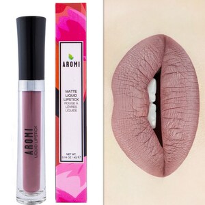 May include: Aromi Matte Liquid Lipstick in a mauve shade. The lipstick is in a clear tube with a black cap. The packaging features the brand name and product description in white text on a pink and red background.