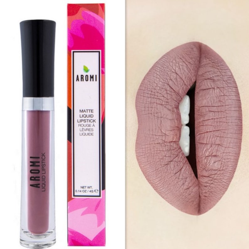 May include: Aromi Matte Liquid Lipstick in a mauve shade. The lipstick is in a clear tube with a black cap. The packaging features the brand name and product description in white text on a pink and red background.