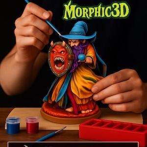 May include: A 3D model mage kit with the text "PAINT YOUR OWN 3D MODEL MAGE KIT" and "Morphic3D". The kit includes a 3D model, 6 acrylic paints, 2 brushes, and a paint tray. The mage figure is painted with blue, orange, and yellow.