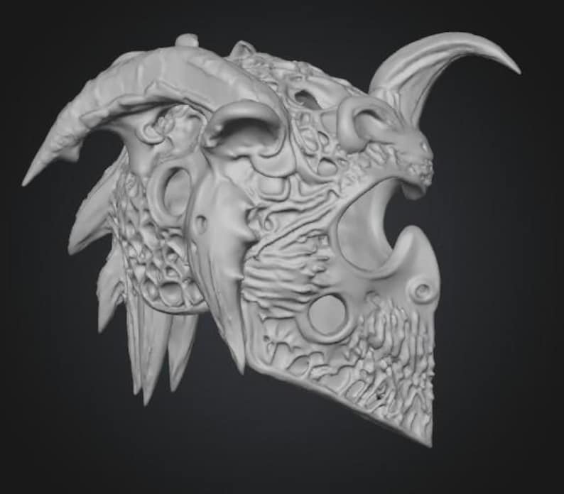 Puede incluir: Un casco de fantas&iacute;a gris claro con intrincadas tallas y un dise&ntilde;o con cuernos. El casco presenta una cara estilizada de drag&oacute;n o demonio con la boca abierta y dientes afilados. El dise&ntilde;o incluye m&uacute;ltiples cuernos y elementos puntiagudos.