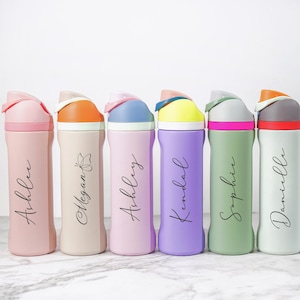 May include: A collection of seven colorful water bottles with flip-top lids. Each bottle is a different pastel color, including pink, beige, purple, green, and white. The bottles are personalized with names in a cursive font.
