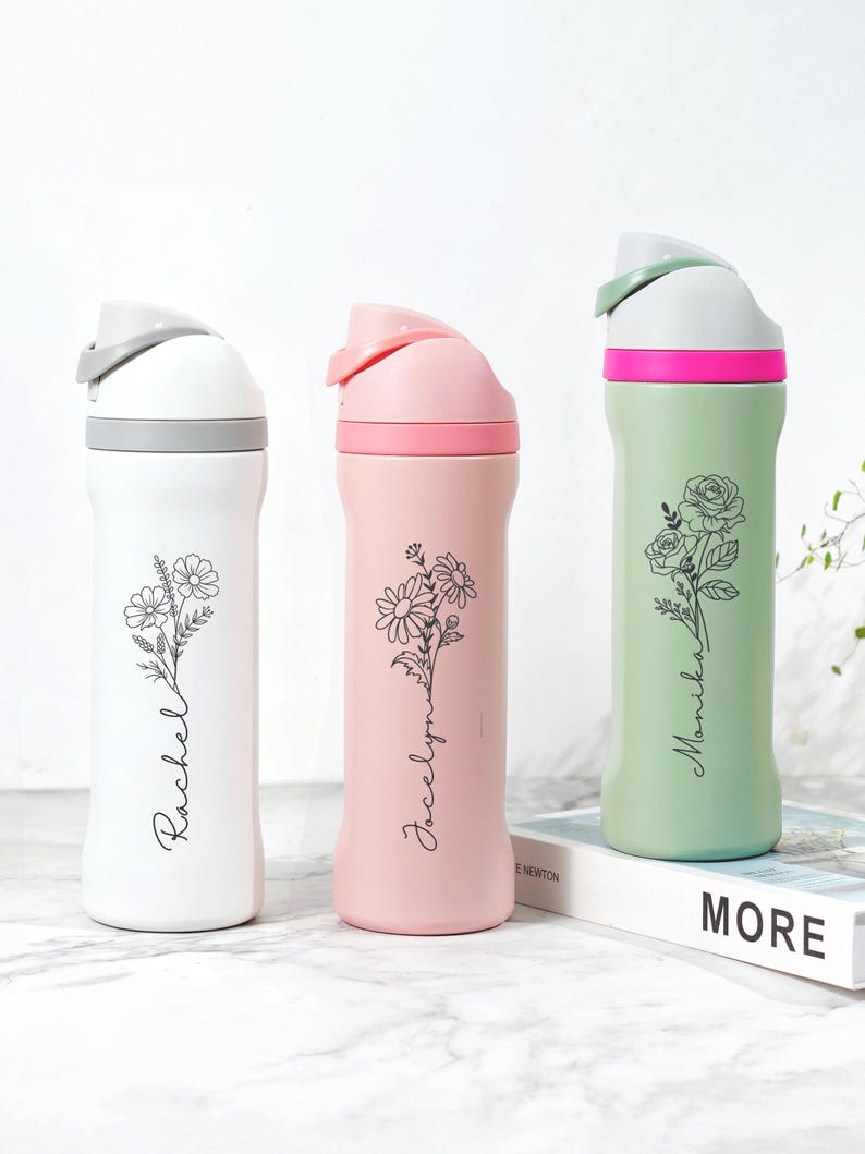 May include: Three insulated water bottles in white, pink, and green. Each bottle features a floral design and a name in a script font. The white bottle has a gray lid, the pink has a pink lid, and the green has a green lid.