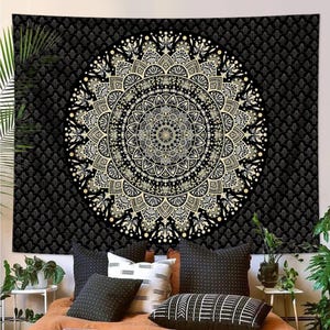 May include: Black tapestry with a large, intricate mandala design in shades of gold and cream. The mandala is centered on a black background with a repeating pattern. This decorative wall hanging adds a bohemian touch to any room.