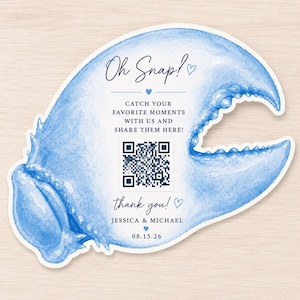 May include: A die-cut sign shaped like a blue watercolor crab claw featuring the text Oh Snap!, Catch your favorite moments with us and share them here!, thank you!, Jessica & Michael, 08.15.26, and a central black and white QR code.