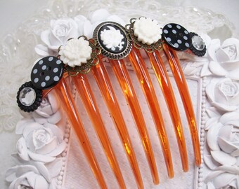 May include: A brown plastic comb with black and white polka dot buttons, white flower embellishments, and a cameo-style button with a black and white design.