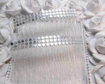 May include: Two clear plastic hair combs featuring a horizontal band of small, reflective silver-toned hexagonal sequins. Each comb has multiple sturdy teeth designed for securing hair, with the metallic embellishment centered on the top edge.