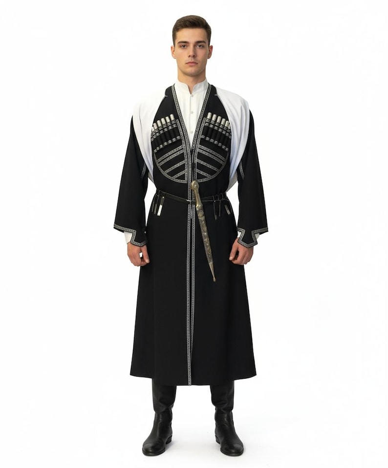 May include: A traditional black Chokha coat with white detailing and silver embroidery. The coat has a white collar and shoulder detail, and is worn with black boots. A dagger is attached to the belt.