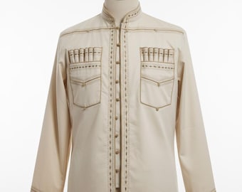 Puede incluir: Una camisa de manga larga color crema con intrincados bordados dorados. La camisa presenta un cuello mandarín, dos bolsillos en el pecho y costuras decorativas en la parte delantera y los puños. La camisa se muestra en un maniquí.