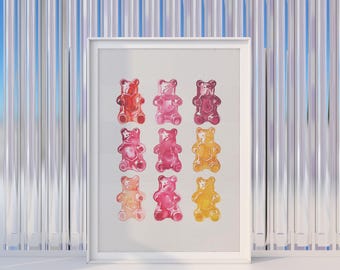 May include: A framed print featuring a grid of colorful gummy bear illustrations. The bears are in shades of red, pink, and yellow. The print is in a white frame, set against a backdrop of vertical silver foil.