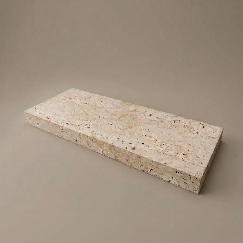 May include: A rectangular shelf made of beige travertine stone with a porous, textured surface. The piece features natural veining and small pits characteristic of the stone, with straight, clean edges forming a solid, flat, horizontal slab.