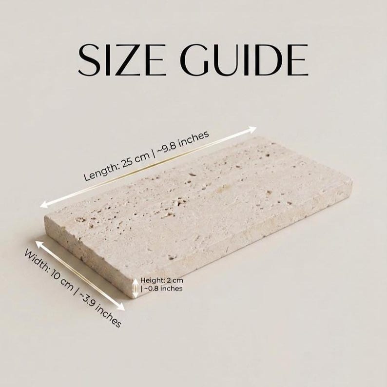 May include: A rectangular beige travertine stone tray with a porous, textured surface. The image includes the text SIZE GUIDE and dimension labels indicating a length of 25 cm (9.8 inches), a width of 10 cm (3.9 inches), and a height of 2 cm (0.8 inches).