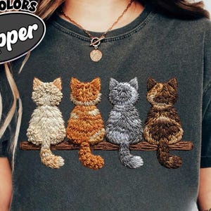 Könnte beinhalten: Eine weiße Keramik-Tasse mit schwarzem Henkel und dem Text "But First, Coffee" in fetter, schwarzer Schrift. Die Tasse steht vor einem neutralen Hintergrund, der ihr schlichtes Design hervorhebt.