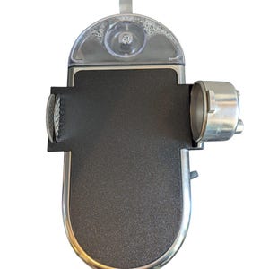 May include: A black and silver espresso machine, viewed from above. It features a clear water reservoir, a textured black surface, and a silver metal portafilter. The design is modern and compact, suitable for making coffee at home or in the office.