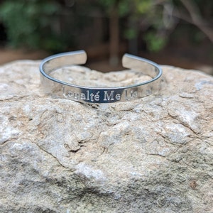 May include: Silver bracelet with the inscription "Loyauté Me Lie".