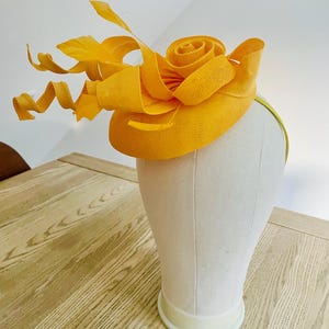 メッシュの渦巻きと羽根が付いた黄色のウェディング ファシネーター。結婚式、レース、アフタヌーン ティー パーティーに最適です。