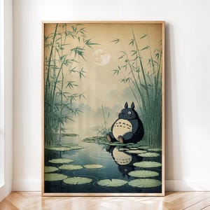 May include: A framed art print depicting a tranquil scene with a large, dark grey creature seated on lily pads in a pond. The background features bamboo stalks, a full moon, and a misty atmosphere, creating a serene, nature-inspired aesthetic.