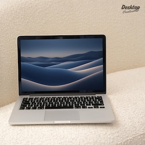 May include: A silver laptop computer with a black keyboard and trackpad. The screen is displaying a blue and white abstract background.
