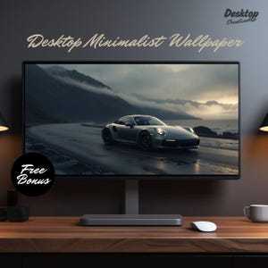 Puede incluir: Un monitor de ordenador de sobremesa que muestra un fondo de pantalla minimalista con un coche deportivo plateado conduciendo por un camino sinuoso con un fondo de montaña brumoso. El monitor está sobre un escritorio de madera con un ratón y una taza.