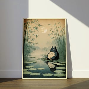 May include: Framed print depicting a tranquil scene with a large, dark blue creature seated beside a pond with lily pads. Tall bamboo stalks frame the water, and a full moon shines in the background. The artwork has a vintage, illustrated style.