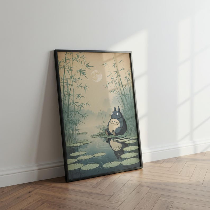 May include: Framed art print depicting a tranquil scene with a large, grey cartoon character seated on lily pads in a pond. The background features bamboo, a full moon, and a misty atmosphere. The artwork is presented in a black frame.