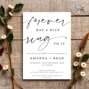 May include: White wedding invitation with black calligraphy text that reads "forever has a nice ring to it". The invitation announces the engagement of Amanda and Brad on Saturday, November 20th at 7:00 PM. The invitation includes the location of the event, The Blue Palm Bar, and RSVP information.
