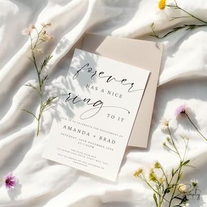May include: White wedding invitation with black calligraphy that reads "forever has a nice ring to it". The invitation is for Amanda and Brad's engagement party on November 20th at 7:00 PM at The Blue Palm Bar.