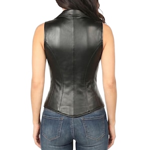 Woman wearing black genuine sheep leather corset vest made from soft real lambskin leather with front zipper, deep V-neck, gold studs and flap pockets, styled with blue jeans - edgy moto biker genuine leather top