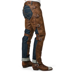 May include: Brown leather chaps with multiple silver buckles over blue denim jeans. The chaps extend from the waist to the ankles, covering the front and sides of the legs. The jeans are cuffed at the ankles, revealing brown leather boots.